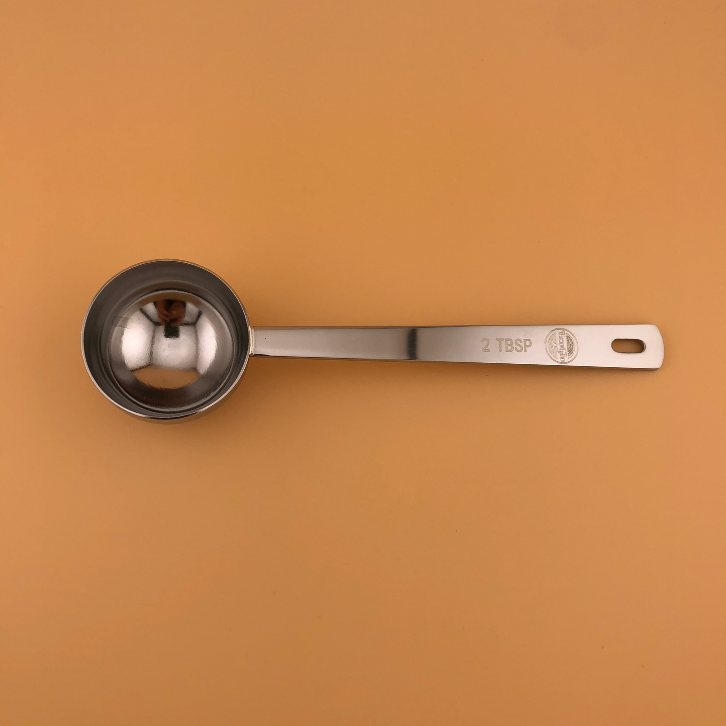 Metal measuring spoon on a brown background
