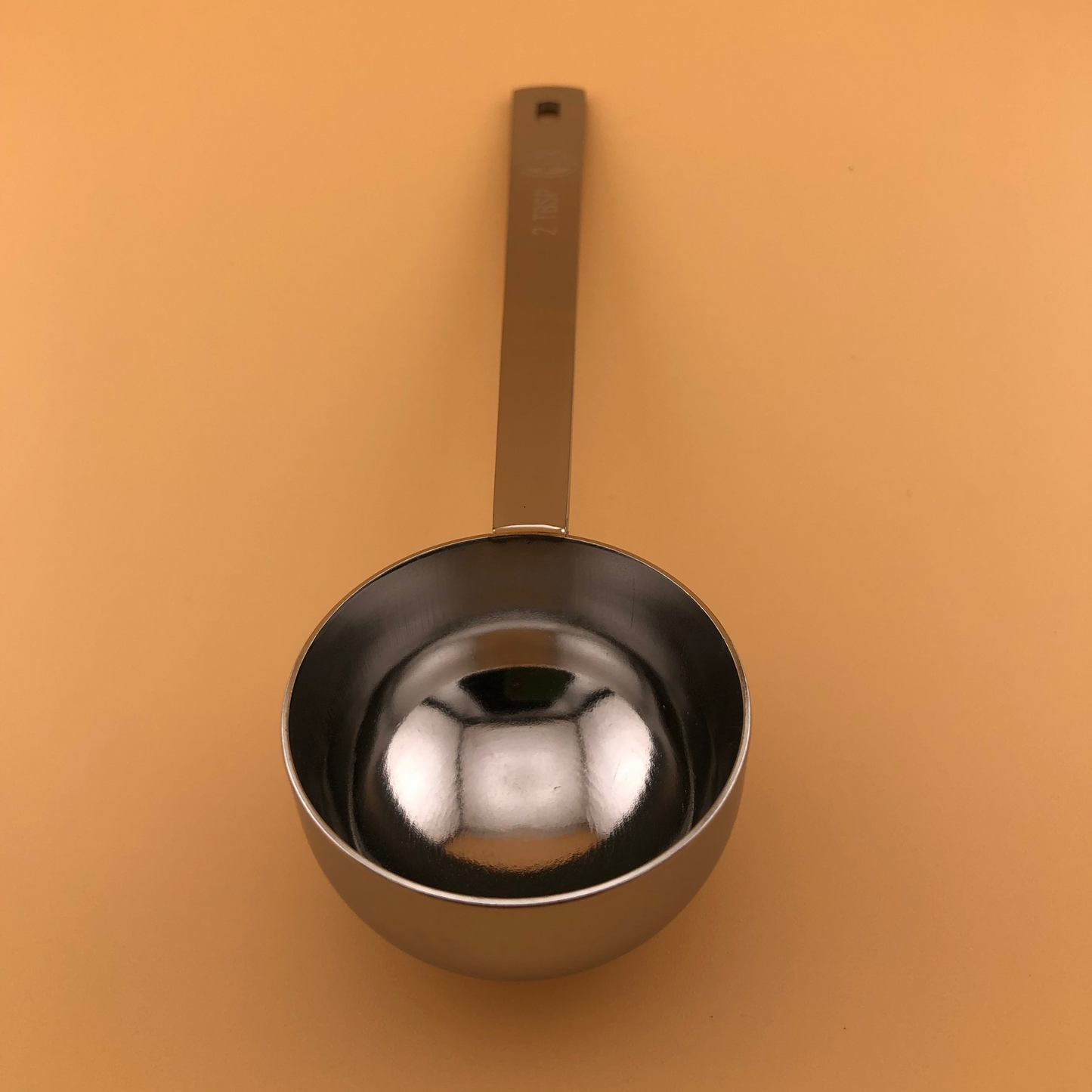 Metal measuring cup on a beige background