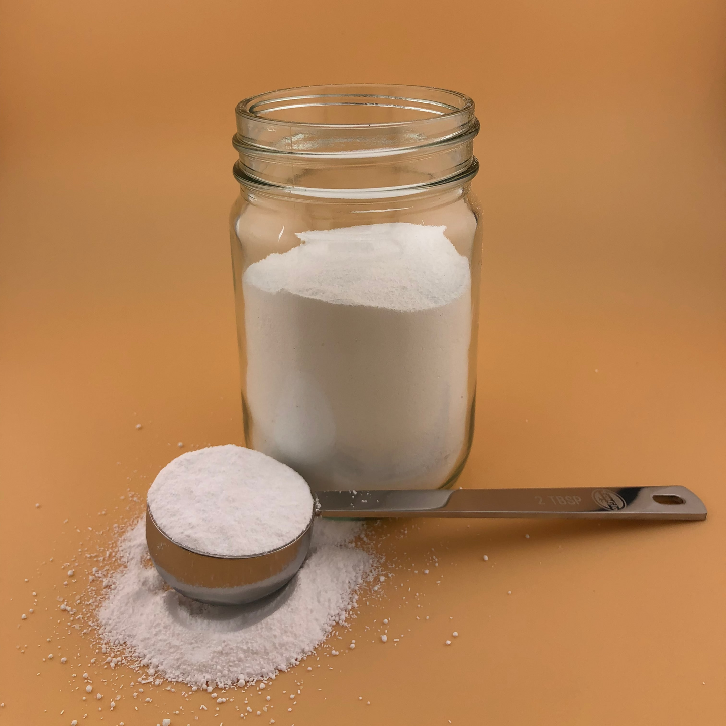 Glass jar and measuring cup filled with detergent on a brown background