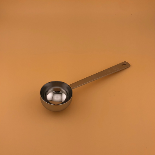 Metal measuring spoon on a brown background