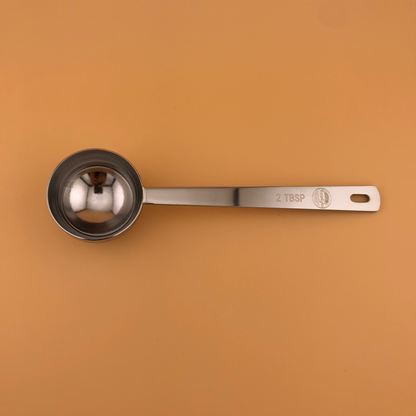 Metal measuring spoon on a brown background